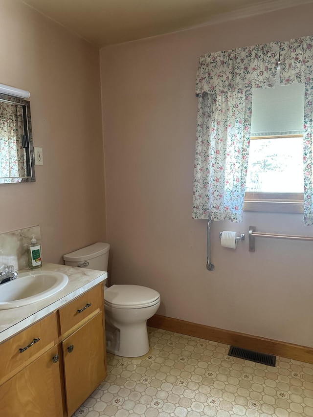 bathroom with vanity, baseboards, visible vents, tile patterned floors, and toilet