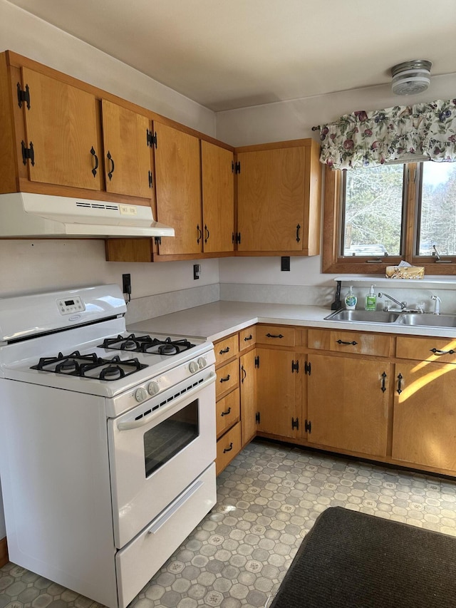 kitchen with under cabinet range hood, a sink, light floors, light countertops, and white range with gas stovetop