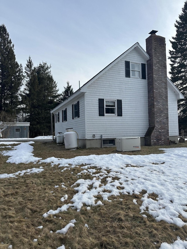 snow covered back of property featuring a chimney