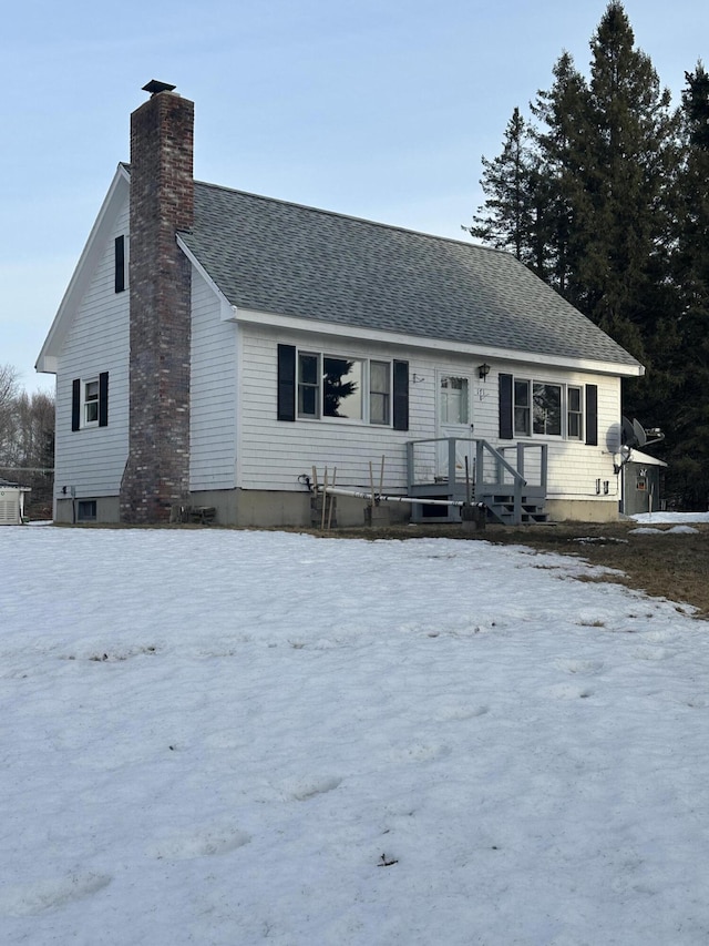 view of front facade featuring roof with shingles and a chimney