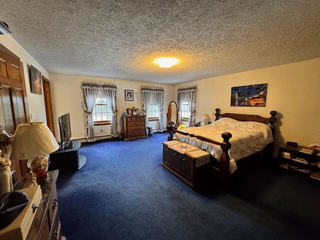 bedroom featuring dark carpet and a textured ceiling