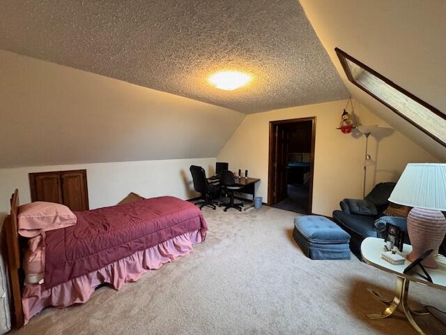carpeted bedroom featuring vaulted ceiling and a textured ceiling