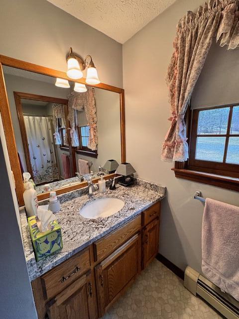 full bathroom featuring a textured ceiling, baseboards, vanity, a shower with curtain, and a baseboard heating unit