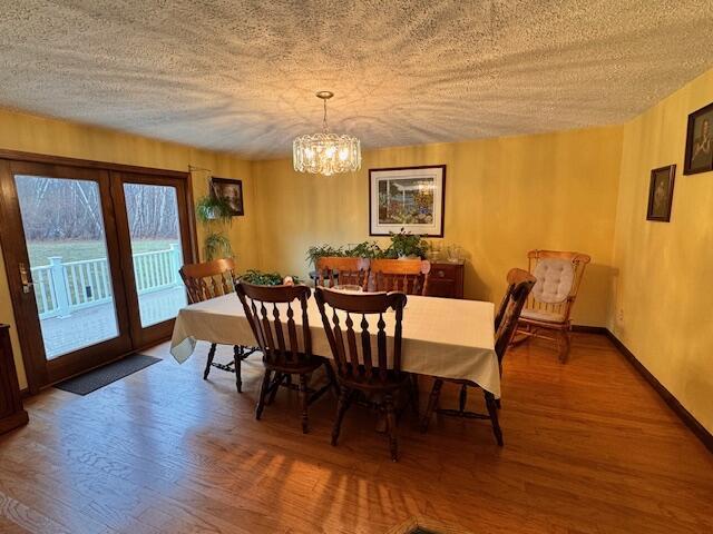 dining area with baseboards, a textured ceiling, wood finished floors, and an inviting chandelier