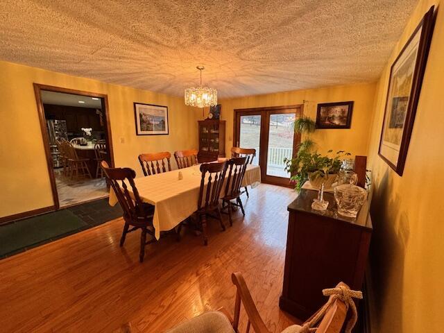 dining space with a textured ceiling, wood finished floors, and an inviting chandelier