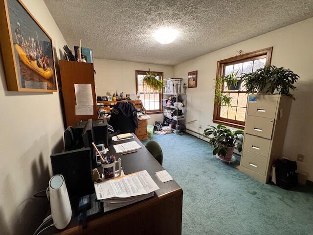 carpeted home office featuring a baseboard heating unit and a textured ceiling