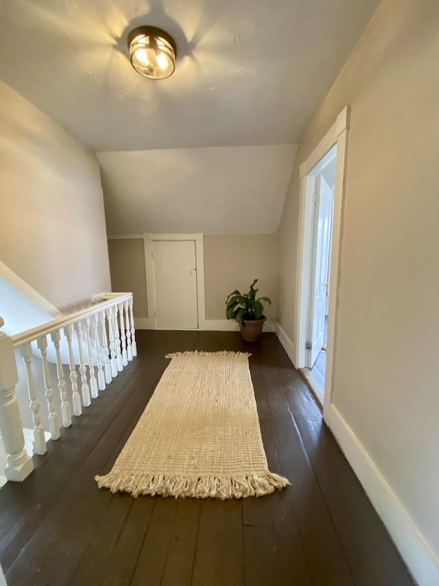 additional living space with baseboards, dark wood finished floors, and lofted ceiling
