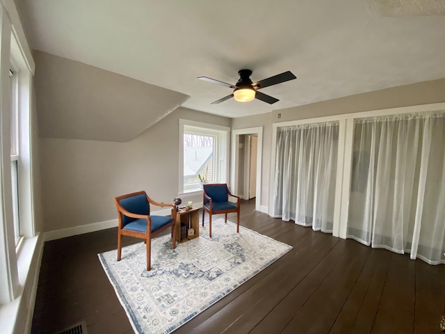 sitting room with a ceiling fan, baseboards, and dark wood-type flooring