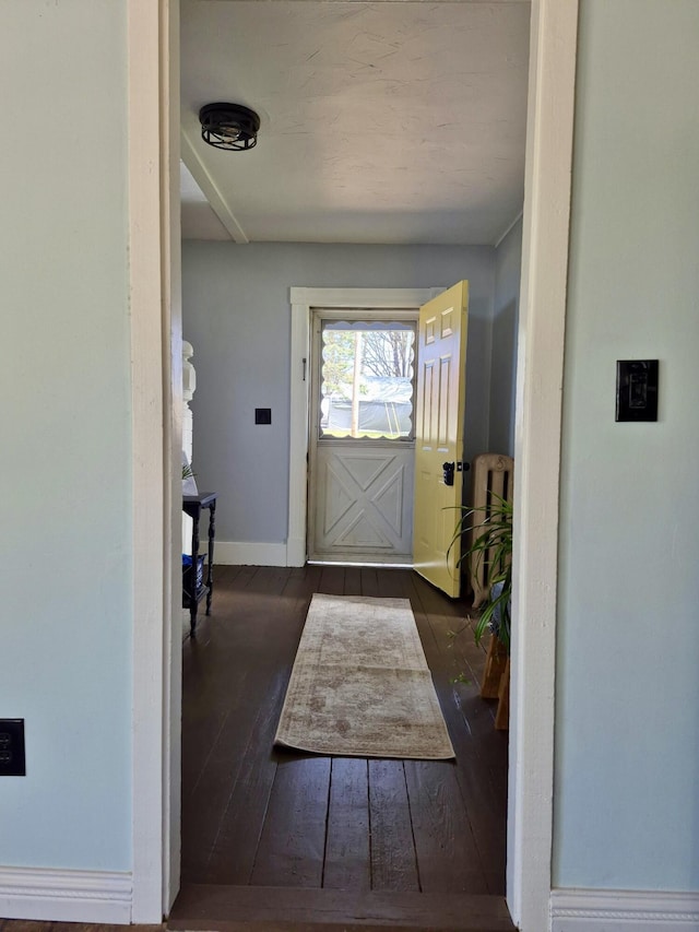 doorway featuring baseboards and hardwood / wood-style flooring