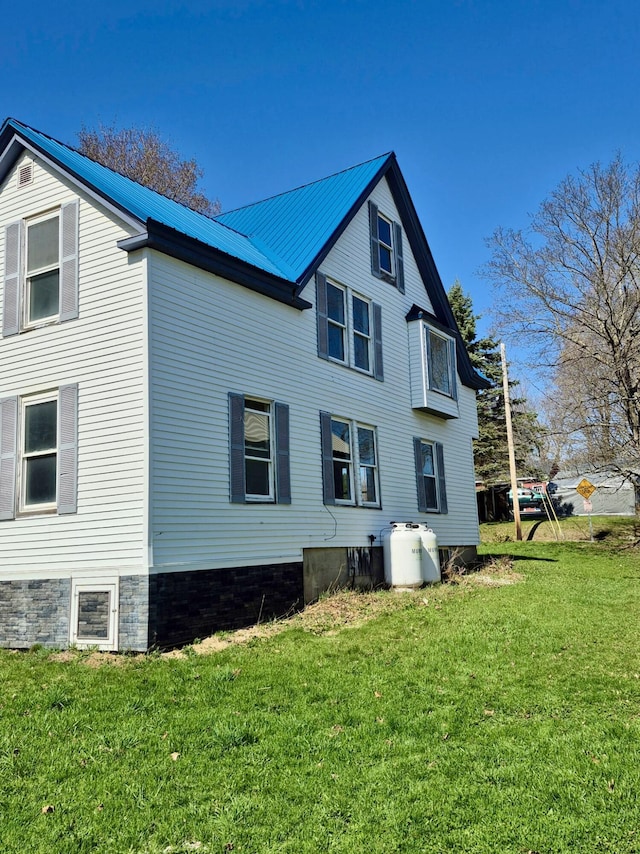 back of property featuring a yard and metal roof