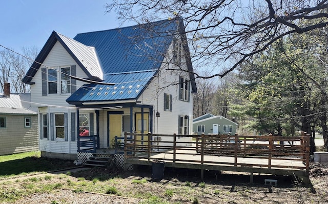 back of property featuring a porch and metal roof