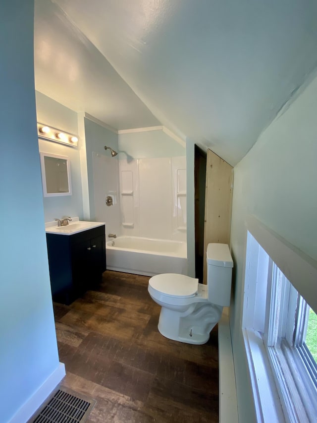 full bathroom with hardwood / wood-style floors, vaulted ceiling, toilet, tub / shower combination, and vanity