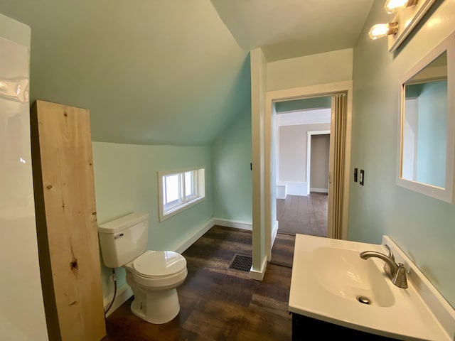 bathroom with wood finished floors, toilet, vanity, vaulted ceiling, and baseboards