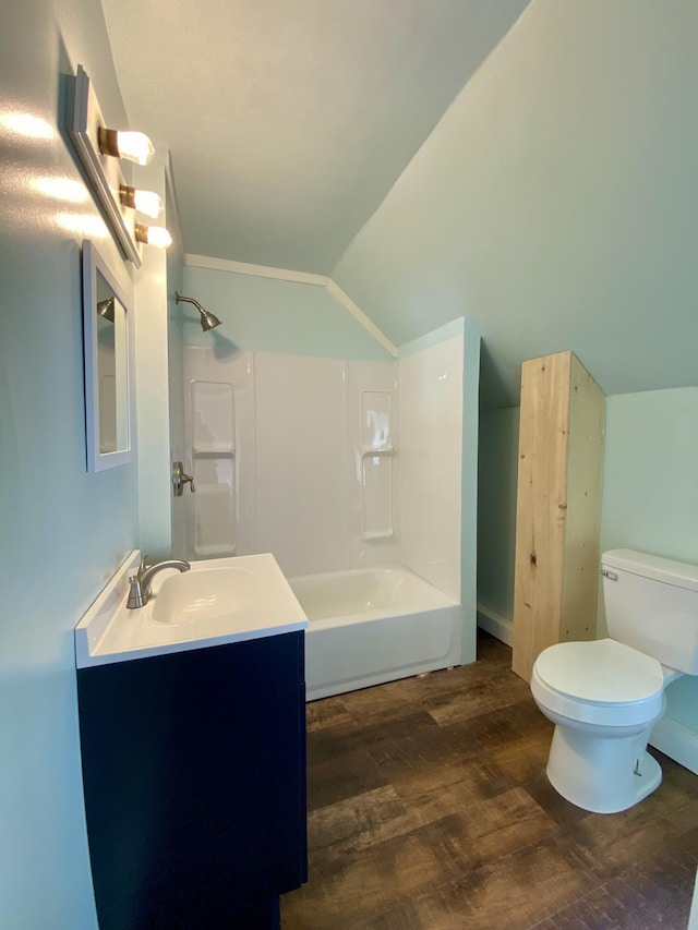 bathroom featuring lofted ceiling, wood finished floors, toilet, bathtub / shower combination, and vanity