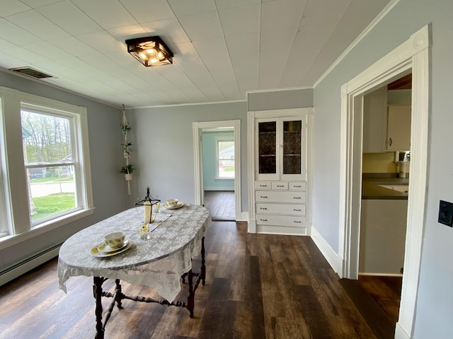 dining space with dark wood finished floors, ornamental molding, baseboard heating, and baseboards