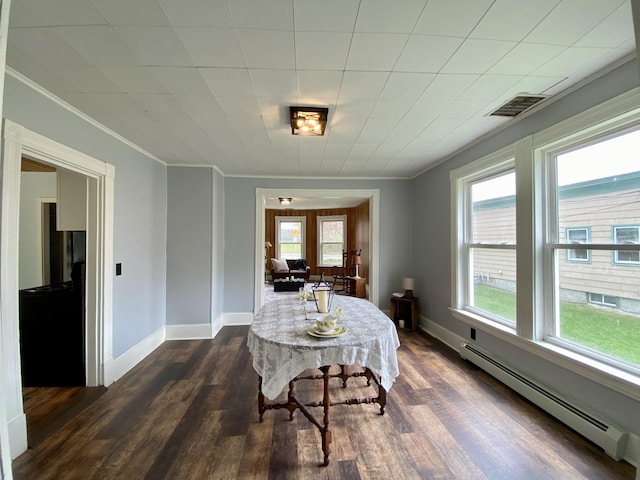 dining room featuring baseboard heating, crown molding, dark wood finished floors, and baseboards