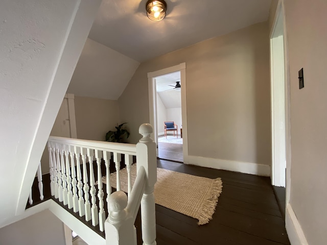 staircase featuring vaulted ceiling, wood-type flooring, and baseboards