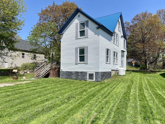 view of home's exterior featuring a lawn and stairway