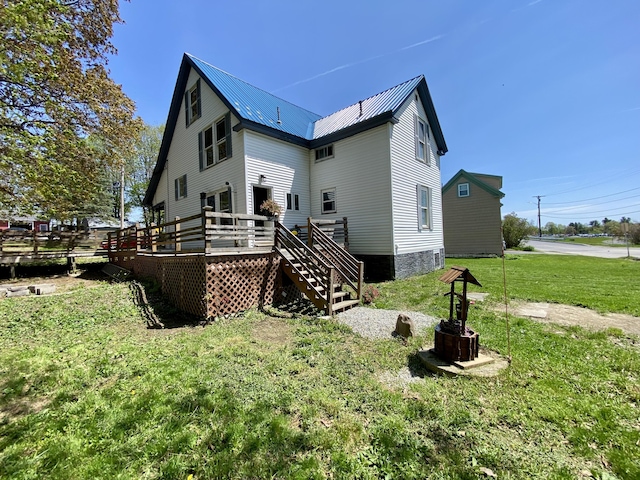 back of property with a deck, a yard, stairs, and metal roof