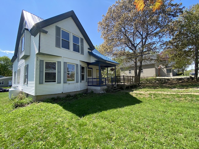 back of house with a lawn, a porch, and metal roof