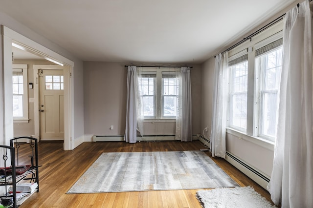 interior space featuring baseboard heating, baseboards, and wood finished floors