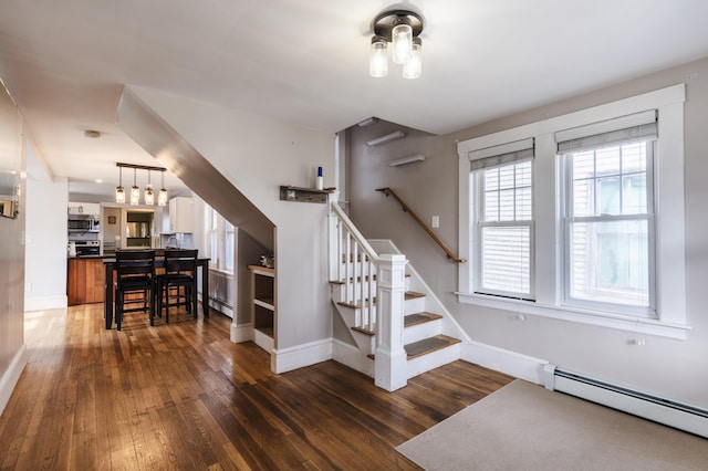 stairway featuring a baseboard heating unit, baseboards, and hardwood / wood-style floors