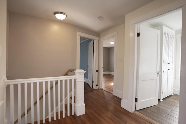 hallway with baseboards, an upstairs landing, and wood finished floors