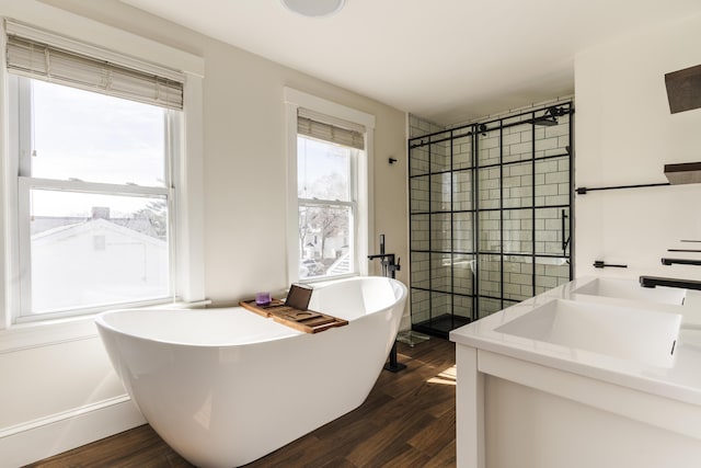 full bath featuring a tile shower, a freestanding tub, vanity, and wood finished floors