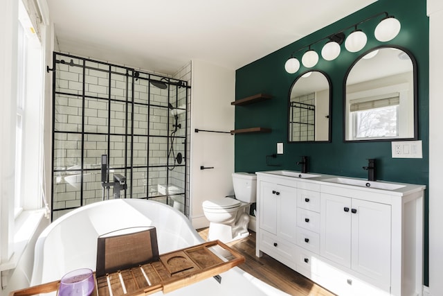 full bath featuring a sink, a freestanding tub, wood finished floors, and a shower stall