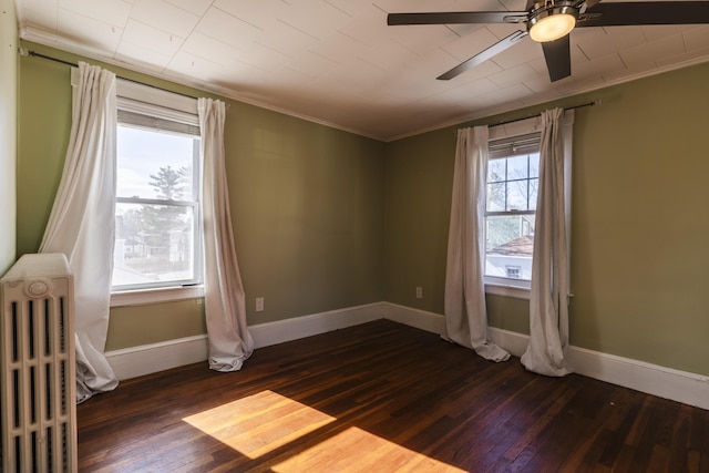 spare room featuring dark wood-type flooring, radiator heating unit, baseboards, and ceiling fan