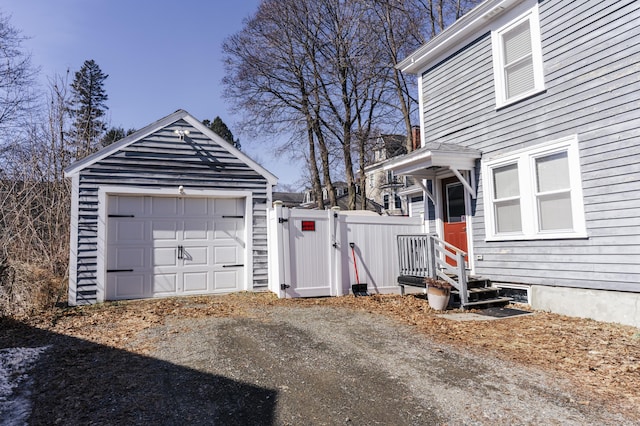 exterior space with fence, a garage, an outdoor structure, driveway, and a gate