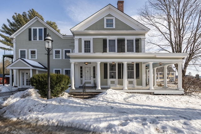 greek revival inspired property with covered porch and a chimney