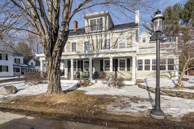 view of front of property featuring a porch, a balcony, and a chimney