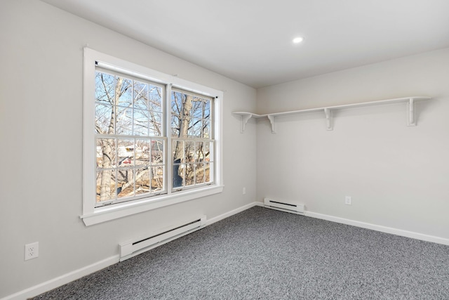 spacious closet featuring a baseboard heating unit and dark carpet