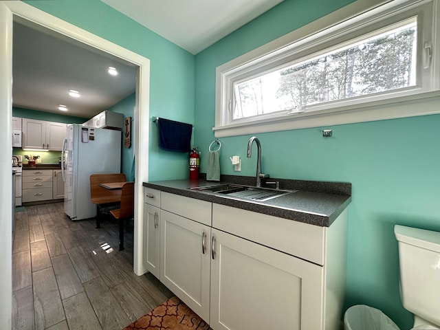 68 Robbins St, Robbinston, ME 04671 - kitchen featuring a sink, dark countertops, white cabinetry, white appliances, and dark wood-style flooring