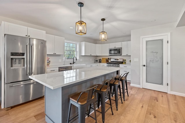 63 Grandview Dr, Newport, ME 04953 - kitchen featuring stainless steel appliances, decorative light fixtures, light wood-style flooring, a breakfast bar area, and white cabinetry