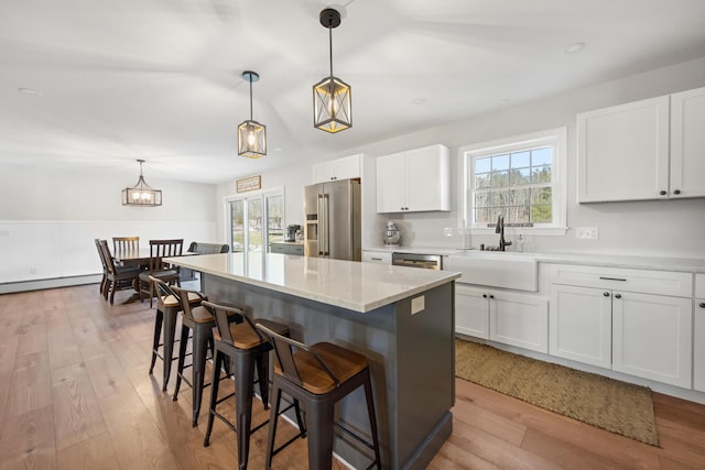 63 Grandview Dr, Newport, ME 04953 - kitchen with stainless steel appliances, a breakfast bar, a sink, a baseboard heating unit, and light wood-type flooring
