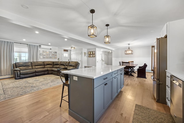 63 Grandview Dr, Newport, ME 04953 - kitchen featuring a wall mounted AC, light wood-style flooring, a kitchen bar, appliances with stainless steel finishes, and decorative light fixtures
