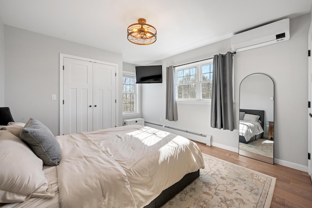 63 Grandview Dr, Newport, ME 04953 - bedroom with baseboards, wood finished floors, a closet, a wall mounted AC, and a baseboard radiator