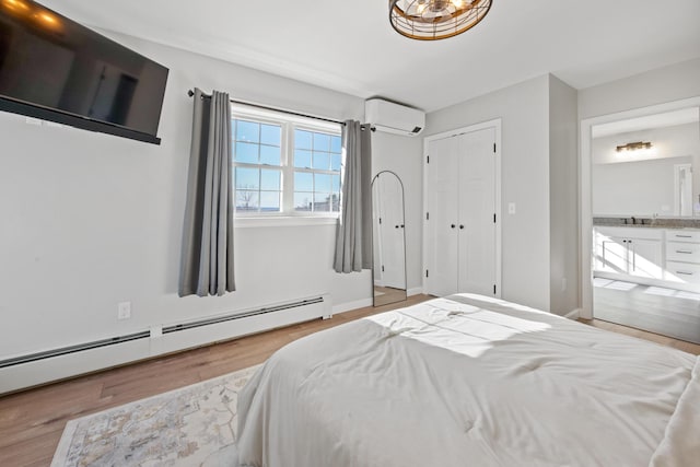 63 Grandview Dr, Newport, ME 04953 - bedroom with wood finished floors, an AC wall unit, a sink, a baseboard radiator, and ensuite bathroom