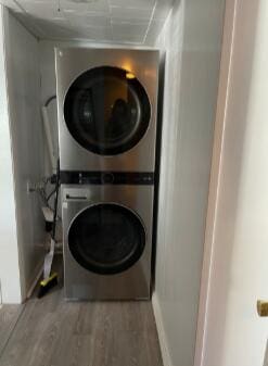 laundry room featuring stacked washer and dryer and wood finished floors
