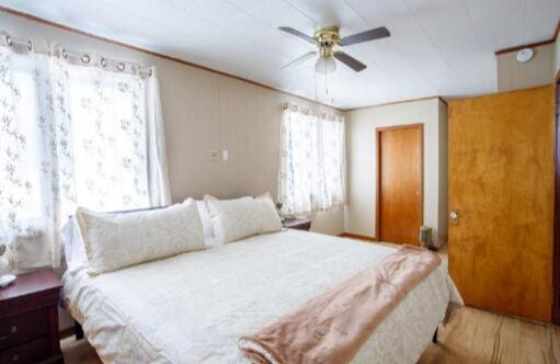 bedroom with wood finished floors, a ceiling fan, and ornamental molding