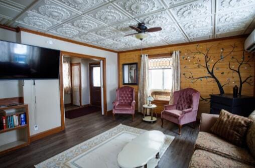 living room featuring wood finished floors, an ornate ceiling, ceiling fan, and crown molding
