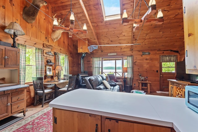 62 Hernborg Rd, Rangeley, ME 04970 - kitchen with a wood stove, light wood-style flooring, wooden walls, a skylight, and brown cabinetry