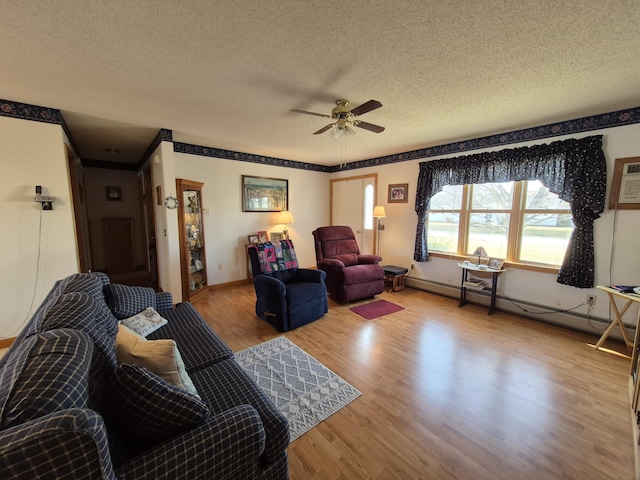 living room with wood finished floors, baseboards, ceiling fan, a textured ceiling, and baseboard heating