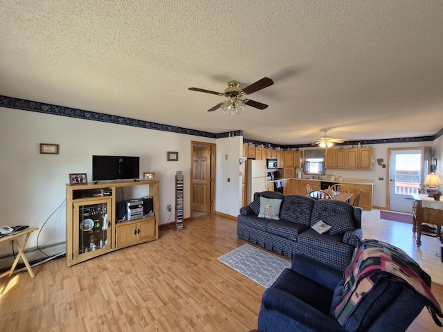 living room with baseboards, ceiling fan, a textured ceiling, and light wood-style floors