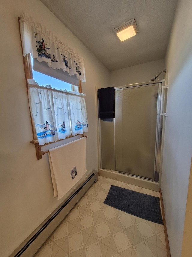 full bath featuring tile patterned floors, a textured ceiling, a shower stall, baseboards, and baseboard heating