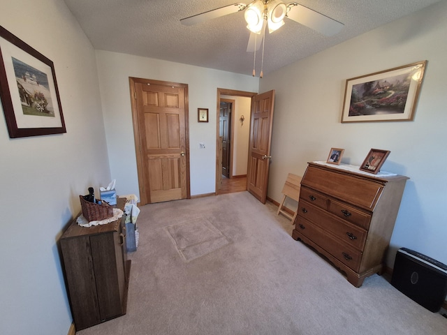 bedroom featuring a ceiling fan, light colored carpet, baseboards, and a textured ceiling