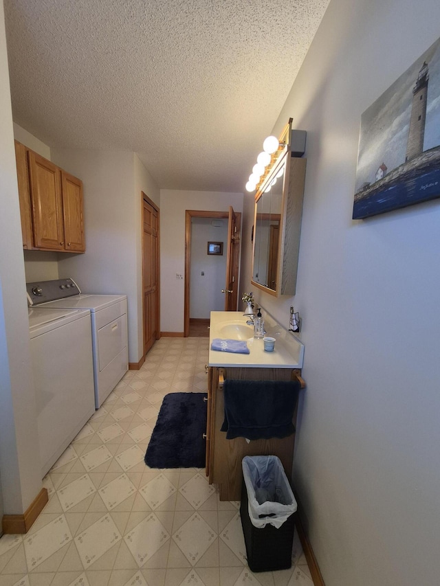 interior space with vanity, baseboards, a textured ceiling, washer and dryer, and tile patterned floors