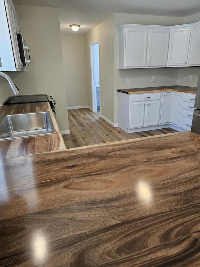 310 Emery Mills Rd, Shapleigh, ME 04076 - kitchen with light wood-type flooring, white cabinets, stove, and stainless steel microwave